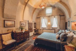 1 dormitorio con 1 cama, 1 silla y ventanas en Kale Konak Cappadocia, en Uchisar