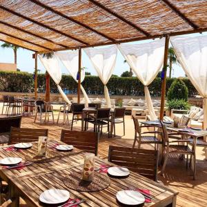 una zona de comedor al aire libre con mesas y sillas y una azotea en El Paraiso Residence Club Mallorca, en Sa Ràpita