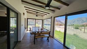 a dining room with a table and large glass windows at Moller Masi - Ayllu Huasi in Purmamarca