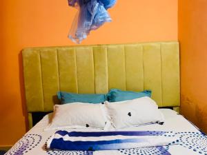 a bed with a green headboard and some pillows at Luanda City Hostel in Luanda