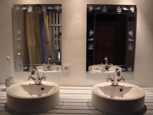 a bathroom with two sinks and two mirrors at La Cense De Renière in Ferrières