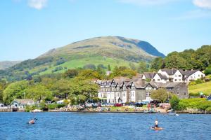 a group of people kayaking on the water in front of a village at Cosy 2 Bedroom Flat in Lake District in Kendal