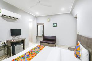 a hotel room with a bed and a chair at FabHotel Sun Om in Raipur