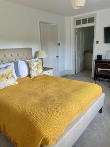 a bedroom with a large bed with a yellow blanket at Denham Mount in Buckinghamshire