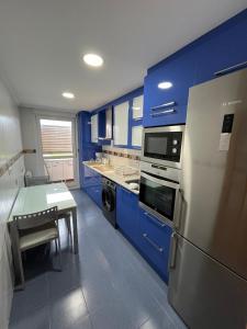 cocina azul con mesa y nevera en Casa Maria en Beranga