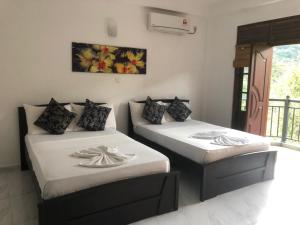 a room with two beds with white sheets at Sun Set Forest Villa in Kandy