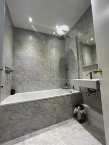 a bathroom with a tub and a sink at Olympia W14 Two-Bedroom Apartment in London