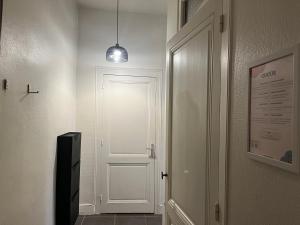 un couloir avec une porte blanche et une lampe pendant dans l'établissement Suite Lavani, à Lyon