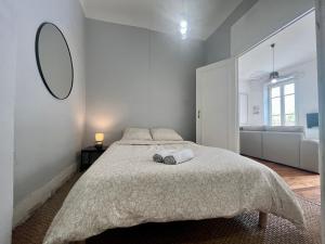 a white bedroom with a large bed and a mirror at Suite Lavani in Lyon