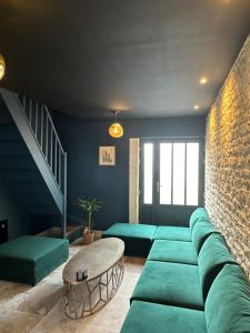 a living room with a green couch and a brick wall at L'ATELIER DU VIEUX BOIS Spa in Bayeux