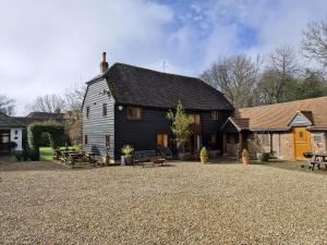 ein großes schwarzes Haus mit einer Terrasse davor in der Unterkunft Walnut Barn - Horsham in Horsham