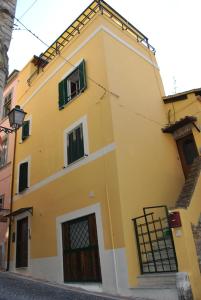 a yellow house with green windows on a street at B&B La Cupella in Monterotondo