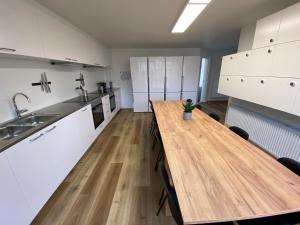 een keuken met witte kasten en een houten tafel bij Q Work - Hostel in Køge