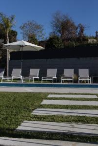 - un groupe de chaises et un parasol à côté de la piscine dans l'établissement Casa do Tourão - Ponte de Lima, à Ponte de Lima