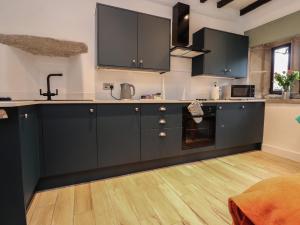 a kitchen with black cabinets and a wooden floor at Pear Tree Cottage at Hey Farm in Barnoldswick