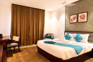 - une chambre avec un lit, un bureau et une chaise dans l'établissement Gokulam Park Guruvayur, à Guruvāyūr