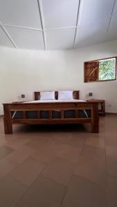 a large wooden bed in a white room at Campement Jamarek in Kafountine