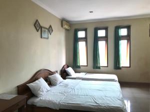 a bedroom with two beds and two windows at Wisma Atma Bhakti near Solo Square Mitra RedDoorz in Lawean