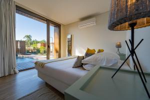 a bedroom with a bed and a large glass window at Pestana Troia Eco-Resort & Residences in Troia