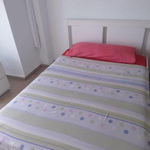 Una cama en un dormitorio con una almohada roja. en Piso compartido cerca de la UNIVERSIDAD CEU, en Moncada