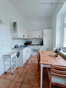 a kitchen with white cabinets and a wooden table at Ferienwohnung Strandmuschel in der Villa Daheim in Juliusruh in Breege