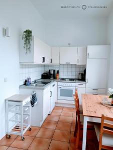 a kitchen with white cabinets and a wooden table at Ferienwohnung Strandmuschel in der Villa Daheim in Juliusruh in Breege
