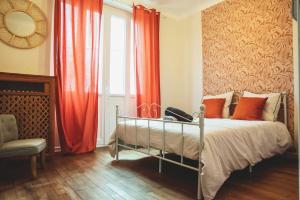 a bedroom with a bed with orange curtains and a mirror at Le Bédier in Angers