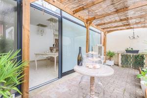 un patio con puertas de cristal y una mesa con una botella de vino en La Dolce Vita à Epernay, en Épernay