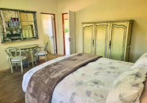 1 dormitorio con 1 cama con mesa y sillas en Imbabali Retreat & Venue, en Magaliesburg