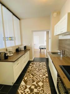 - une cuisine avec des placards blancs et un tapis au sol dans l'établissement Le Gîte Du Parc avec parking vieux port et plage au calme, à La Rochelle