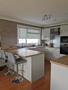 a kitchen with white cabinets and a large island at River View - Norfolk Broads in Brundall