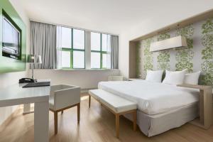 Un dormitorio con una gran cama blanca y un escritorio. en NH Amsterdam Noord, en Ámsterdam