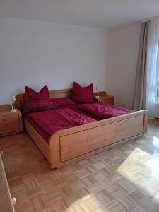 Un dormitorio con una gran cama de madera con sábanas rojas. en Grashüpfer en Freiensteinau