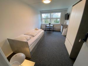 Q Work - Hostel في كوغ: غرفة نوم بسرير وطاولة ونافذة