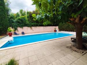 una piscina con un árbol al lado en Chambre double avec piscine 15 mn du Cap d'Agde, en Saint-Thibéry