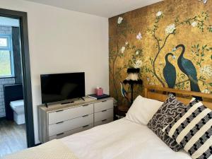 a bedroom with a bed and a wall with a mural of birds at Lovely independent 1-Bed Apartment in Freshwater in Freshwater