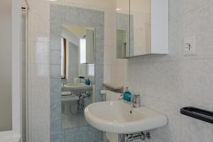 La salle de bains blanche est pourvue d'un lavabo et d'un miroir. dans l'établissement Garda Doma, à Brenzone