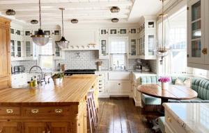cocina con armarios blancos y mesa de madera en White Cottage, en Chester