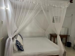 Una cama con cortinas blancas en un dormitorio. en New Bimal Villa, en Bentota