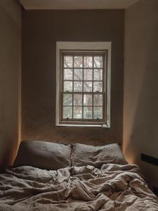 an unmade bed in a room with a window at Loggia Studio in Edinburgh