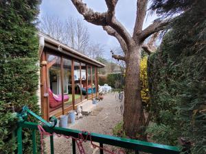 a house with a tree next to a fence at Mobile home toutes saisons in Beauzac