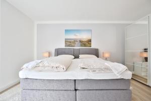 een slaapkamer met een groot bed met witte lakens bij Appartemenhaus Linda-Lu Appartementhaus Linda-Lu Appartement 1 in Scharbeutz