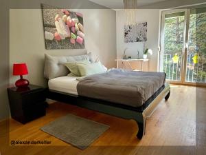 a bedroom with a bed with a red lamp and a window at Schönes und ruhiges Privatzimmer mit französischem Balkon in Munich