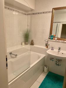 a white bathroom with a tub and a sink at Schönes und ruhiges Privatzimmer mit französischem Balkon in Munich