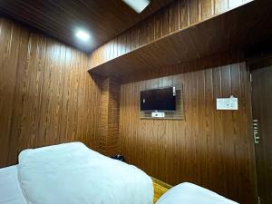 een slaapkamer met een bed en een tv aan een houten muur bij Hotel Grand Villa in Mumbai