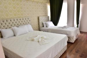 two beds in a hotel room with white sheets at MELLES OTEL in Antalya