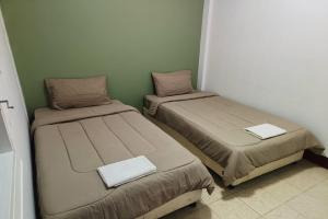 two beds in a small room with green walls at Andaman Residence in Thalang