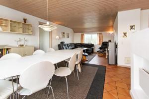 uma sala de estar com uma grande mesa branca e cadeiras em Cottage with wood-burning stove by the sea - SJ760 em Harboør