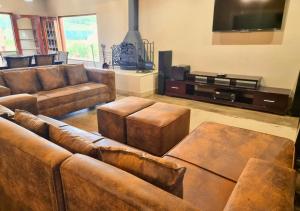 sala de estar con muebles de cuero marrón y TV de pantalla plana. en Imbabali Retreat & Venue, en Magaliesburg