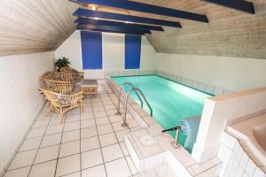 uma piscina num quarto com mesa e cadeiras em Thatched house with spa and pool by the sea - SJ67 em Harboør